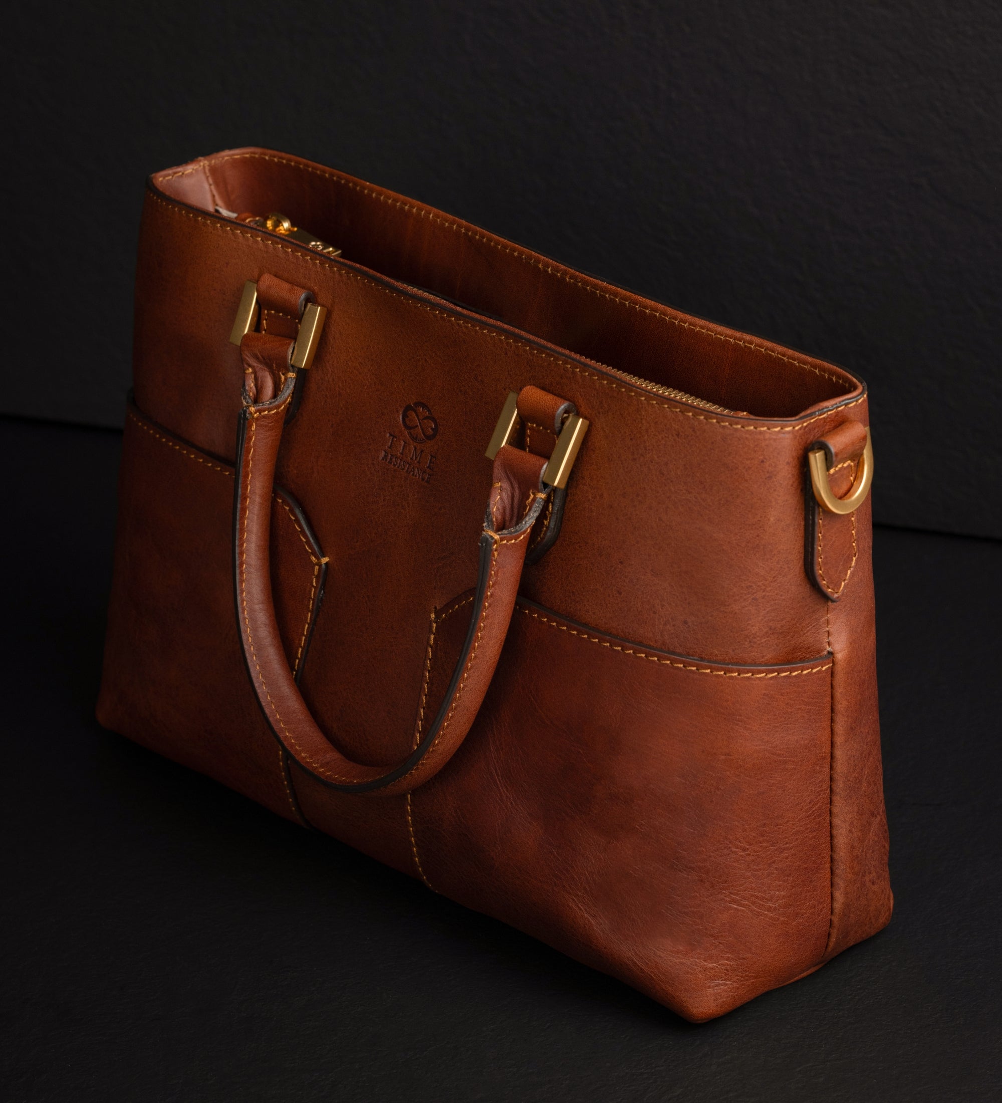Cognacbraune Camilla Schultertasche schräg gezeigt, mit D-Ring und aufgesetzten Taschen