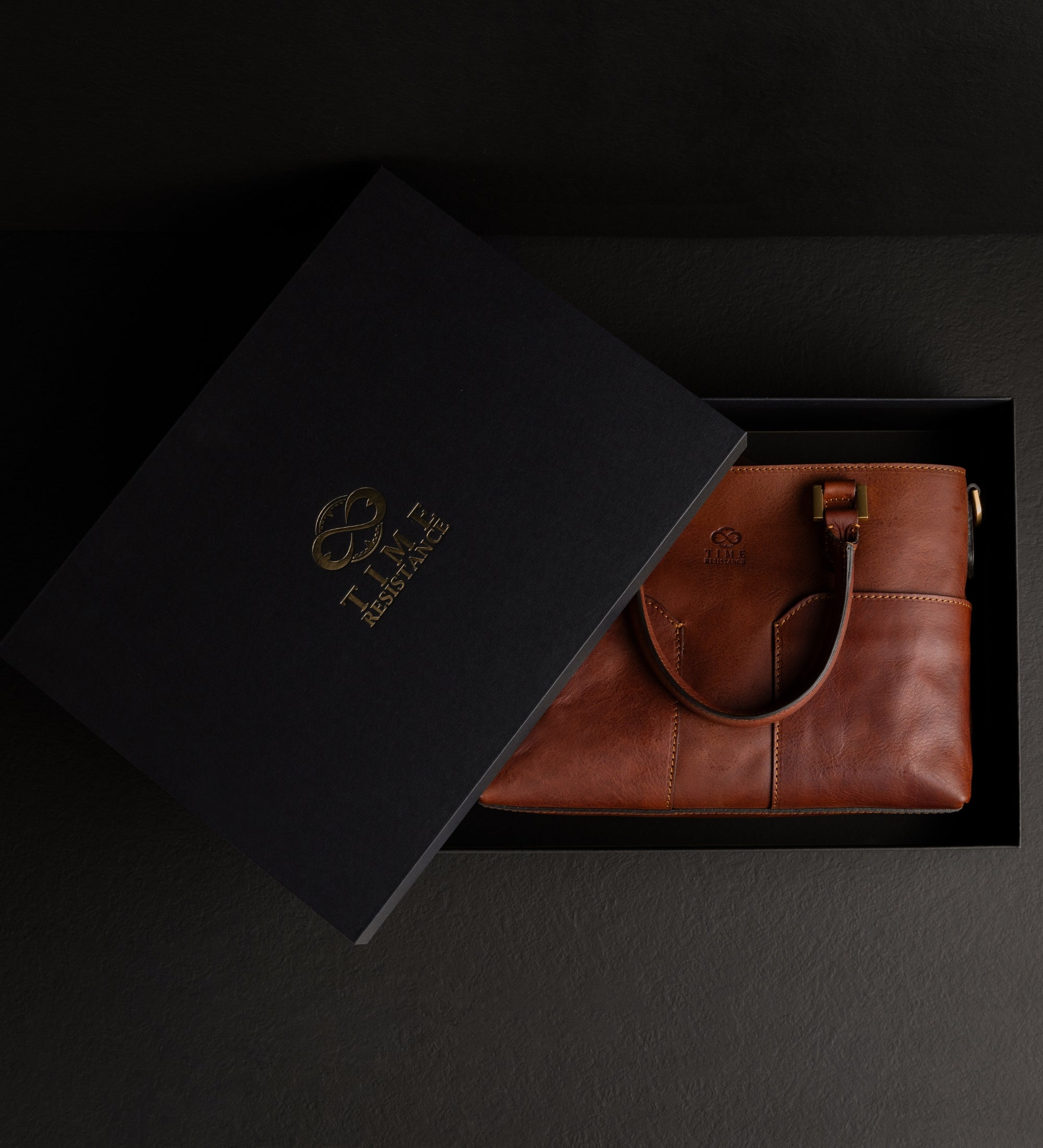 Geöffnete schwarze Geschenkbox mit der cognacbraunen Camilla Schultertasche aus Leder darin